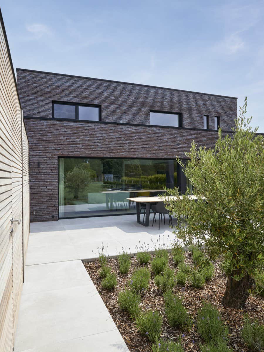 nieuwbouw woning in Lennik terras in beton gevelsteen en houten bijgebouw